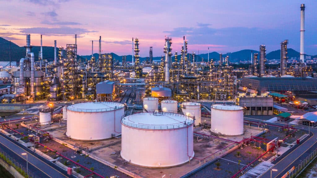 Large white storage tanks equipped with a magnetic level gauge at an oil refinery, with mountains in the background at sunset.