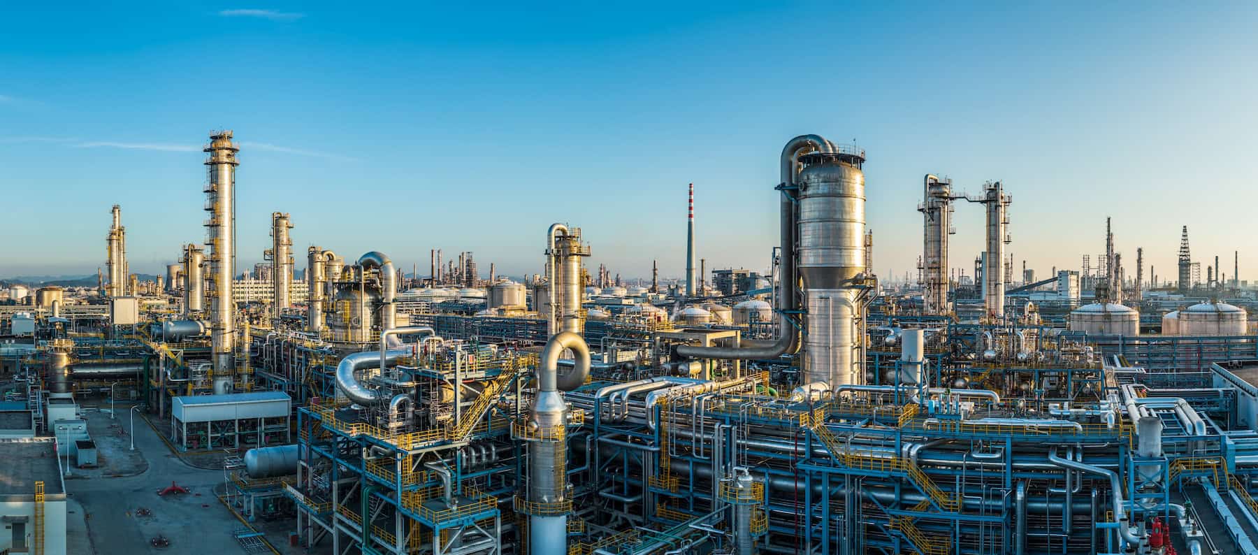 A large oil refinery and petrochemical plant with complex industrial equipment at sunset